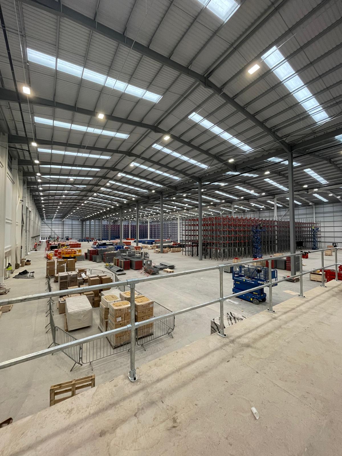 new-build warehouse electrical installation, lit floor seen from the mezzanine
